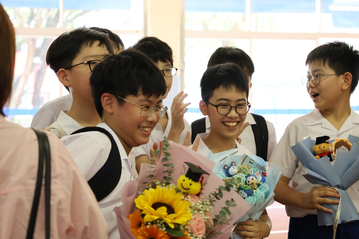 A group of young boys in uniform holding flowersDescription automatically generated